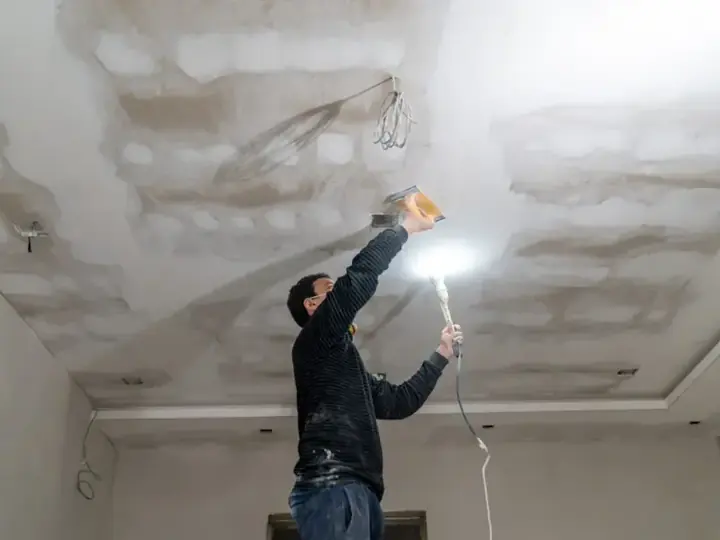 Tech checking a water-stained ceiling with a work light before drying starts