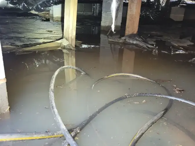 Standing water over a torn vapor barrier in a flooded crawl space in Mooresville, NC