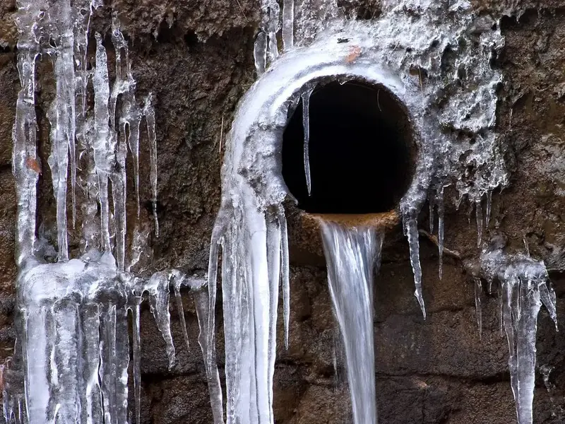 Ice built up around a frozen pipe outlet during a hard North Carolina freeze
