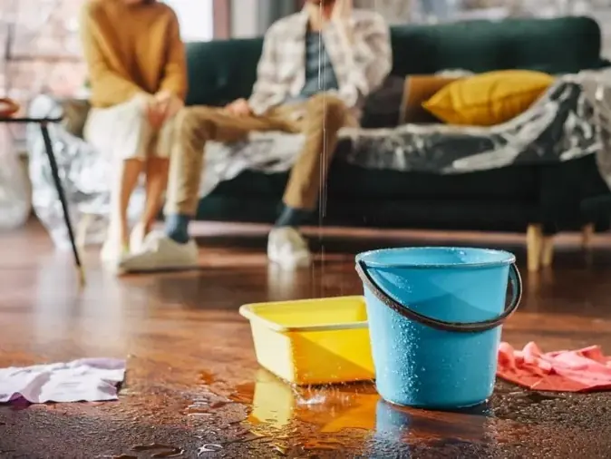 Buckets catching a roof leak dripping onto a living room floor in Mooresville
