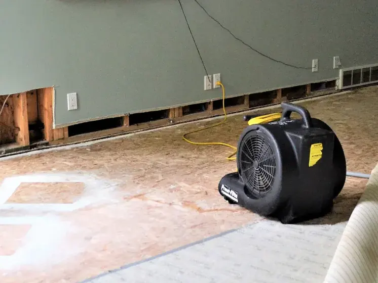 Air mover drying a subfloor beside a flood cut in a Mooresville room